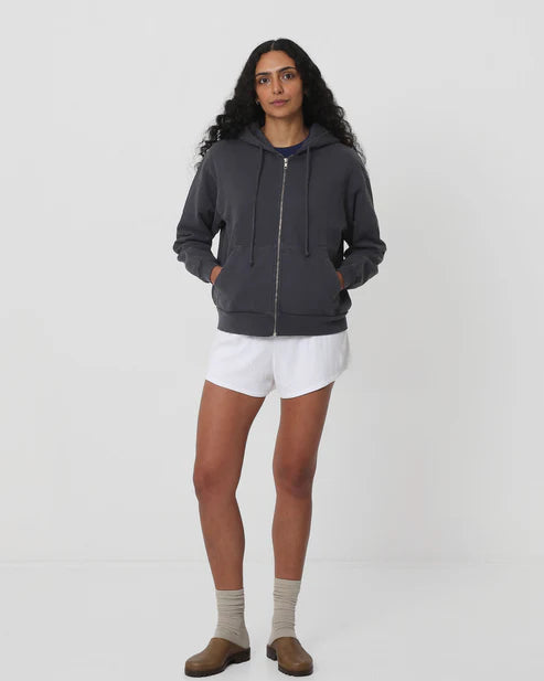 Person wearing a dark gray hoodie, white shorts, and brown shoes on a white background
