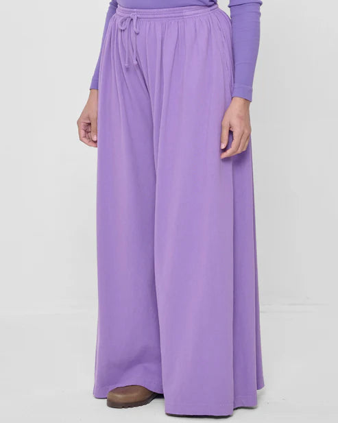 Person wearing a long-sleeve top and wide-leg pants in a light purple color on a white background