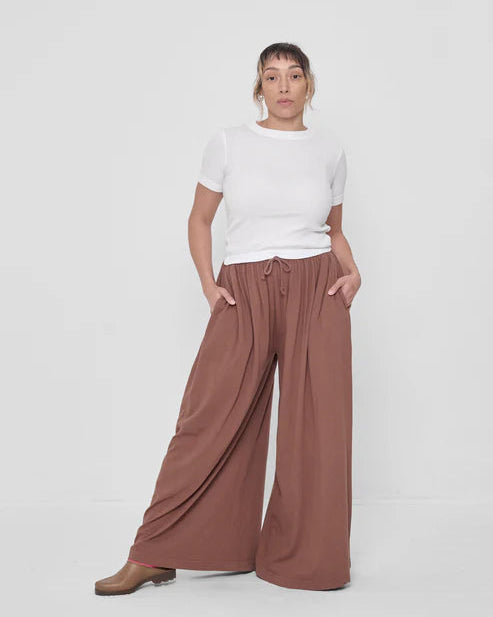 Person wearing a white t-shirt and brown wide-leg pants on a white background