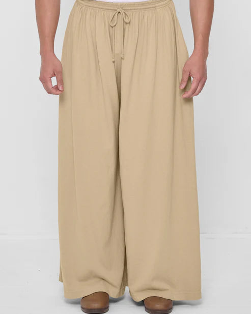 Person wearing beige wide-leg pants on a white background