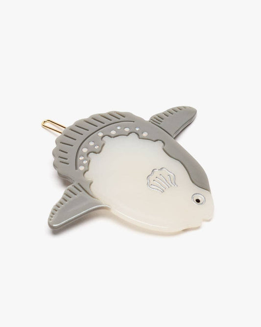 Fish-shaped hair clip with a white and gray design on a light beige background