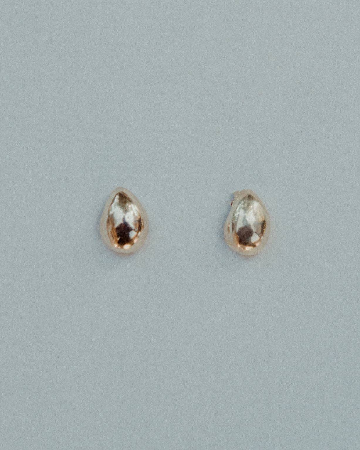 Pair of gold earrings with gemstones on a light gray background