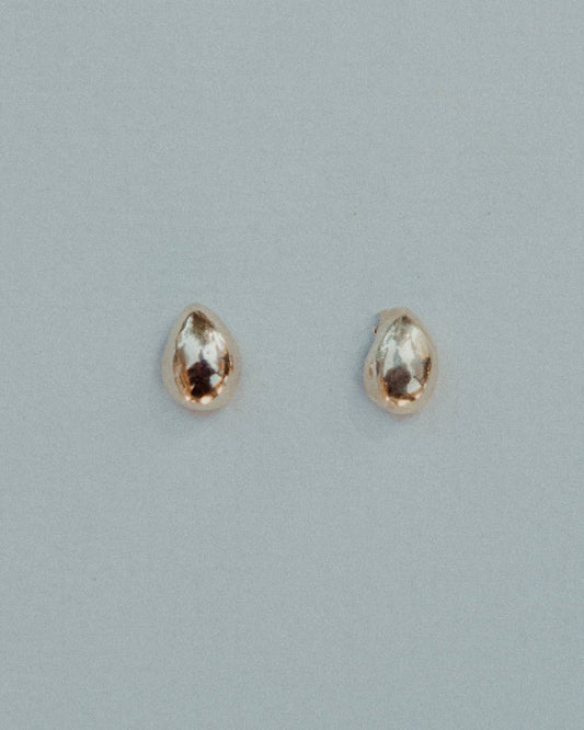 Pair of gold earrings with gemstones on a light gray background