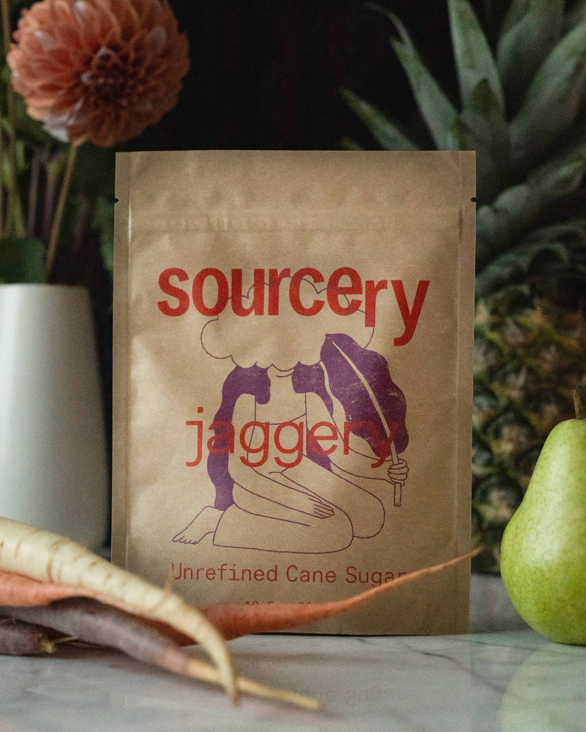 Sourcery jaggery package on a table with vegetables and flowers in the background