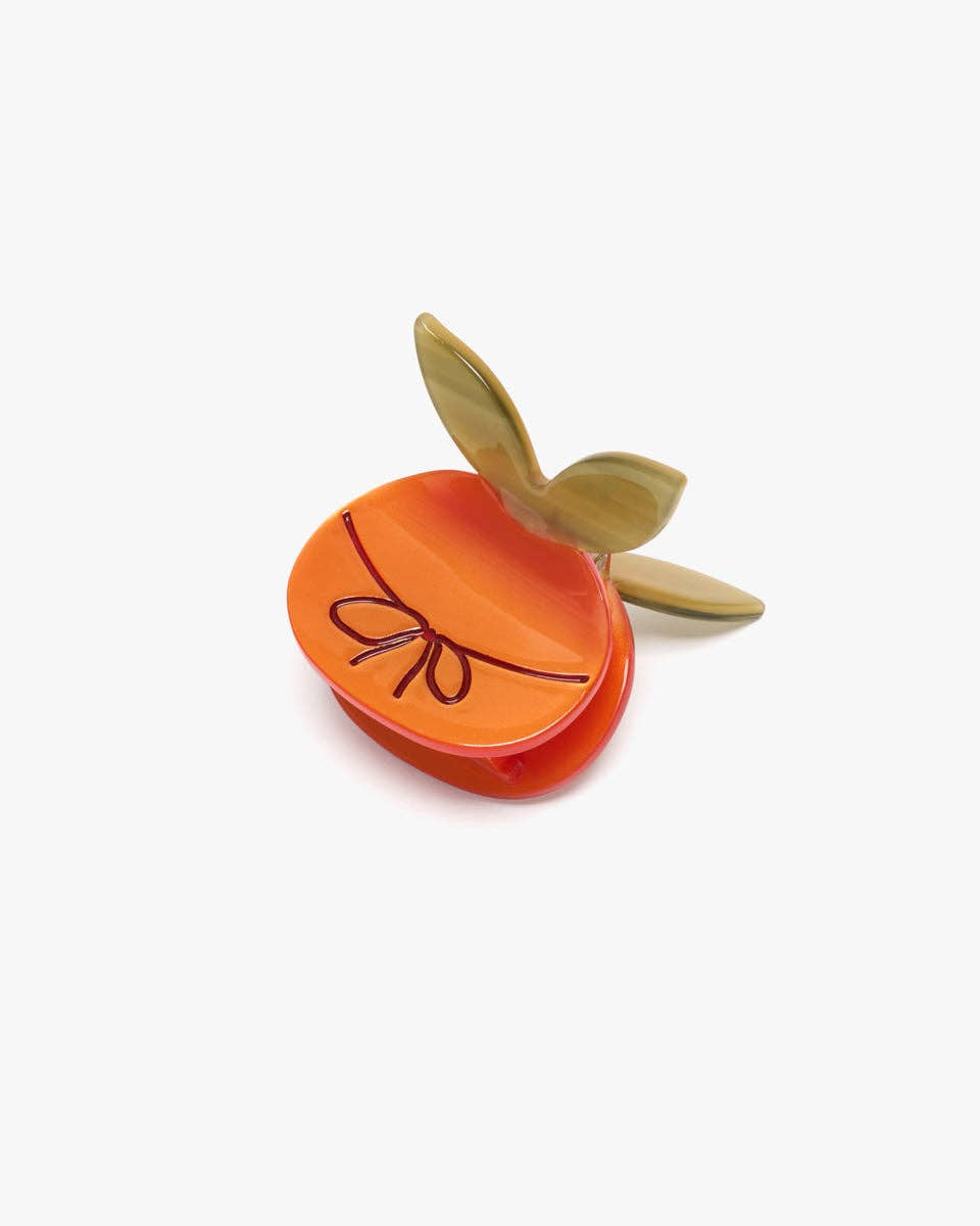 Small orange container with a leaf on a white background