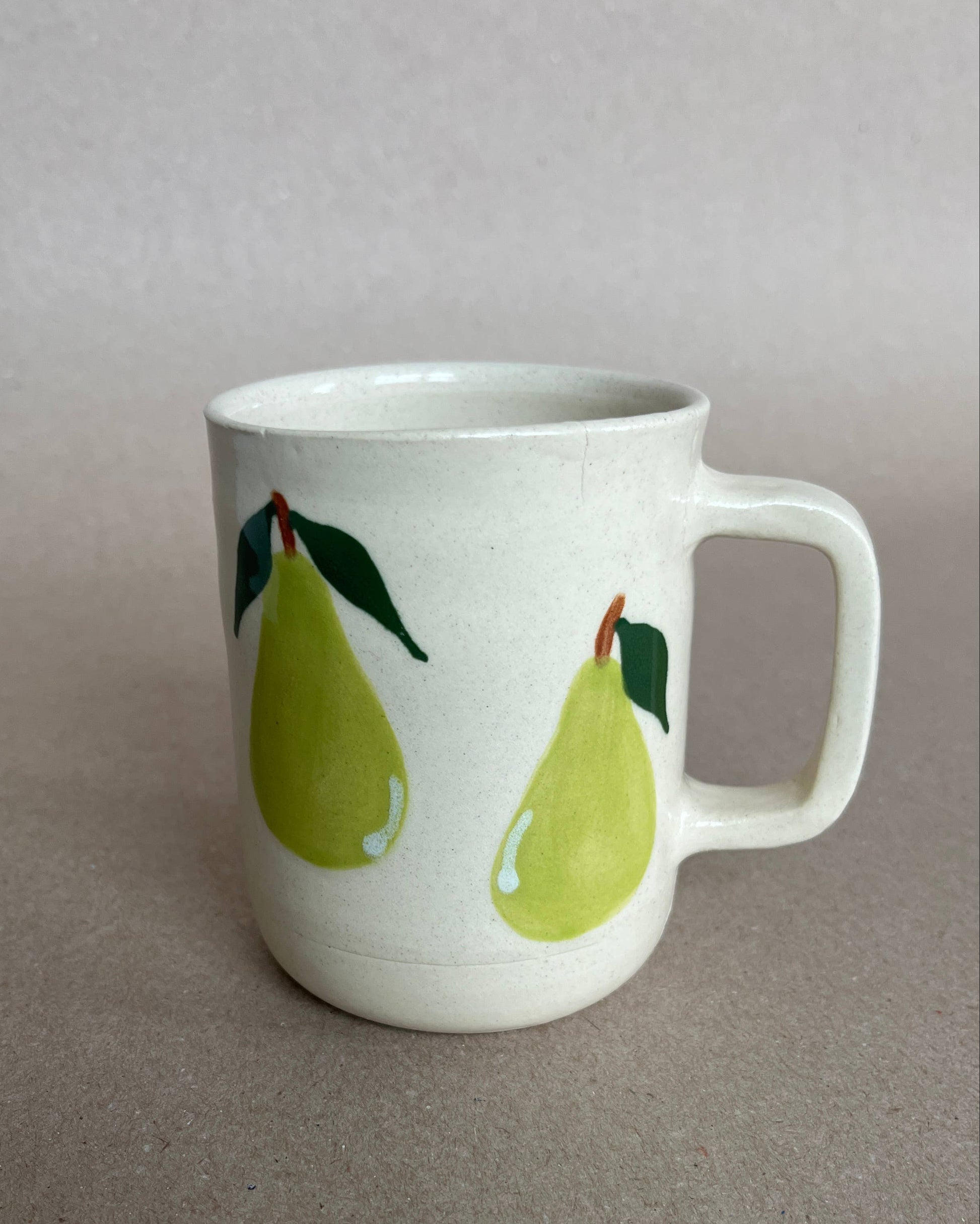 White mug with green pear illustrations on a gray background