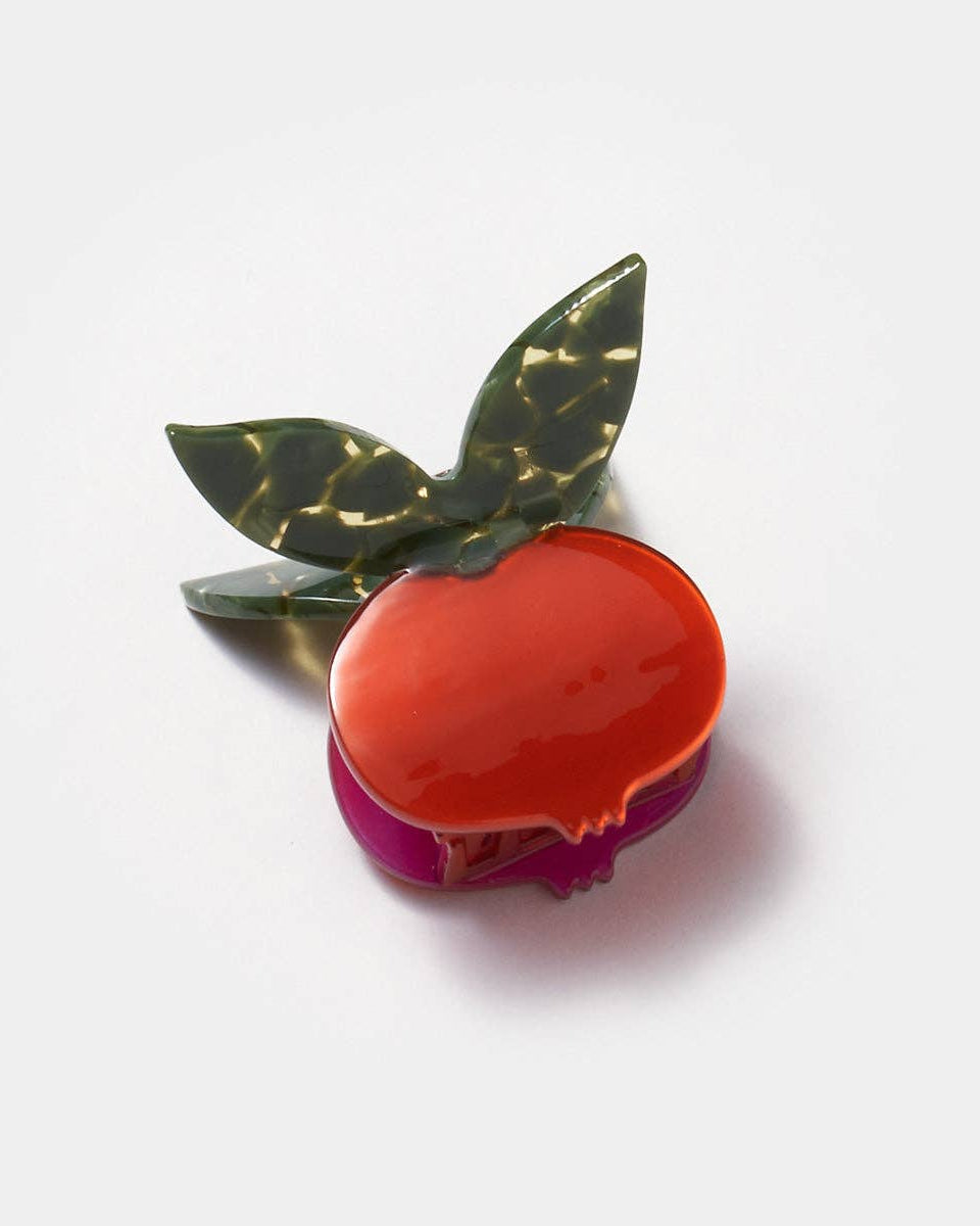 Decorative brooch shaped like a red apple with green leaves on a white background