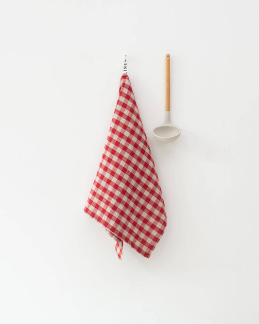 Red and white checkered towel hanging on a hook with a white wall background
