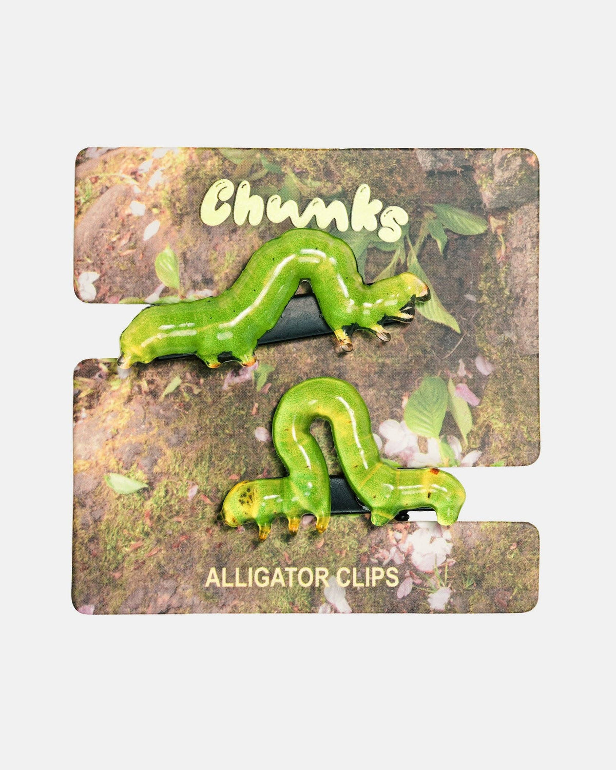 A pair of green caterpillar-shaped alligator clips attached to a printed display card labeled 'Chunks' and 'ALLIGATOR CLIPS' on a light gray background.