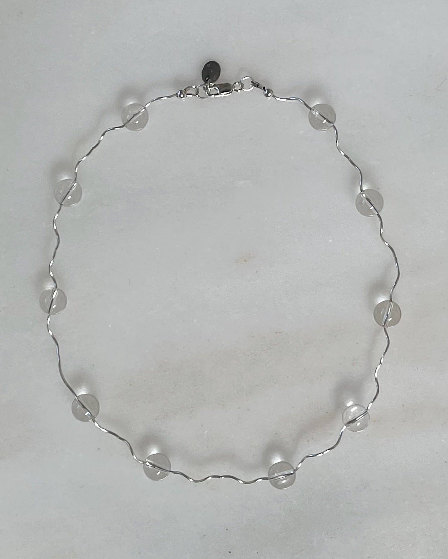 Silver necklace with clear beads on a light gray background