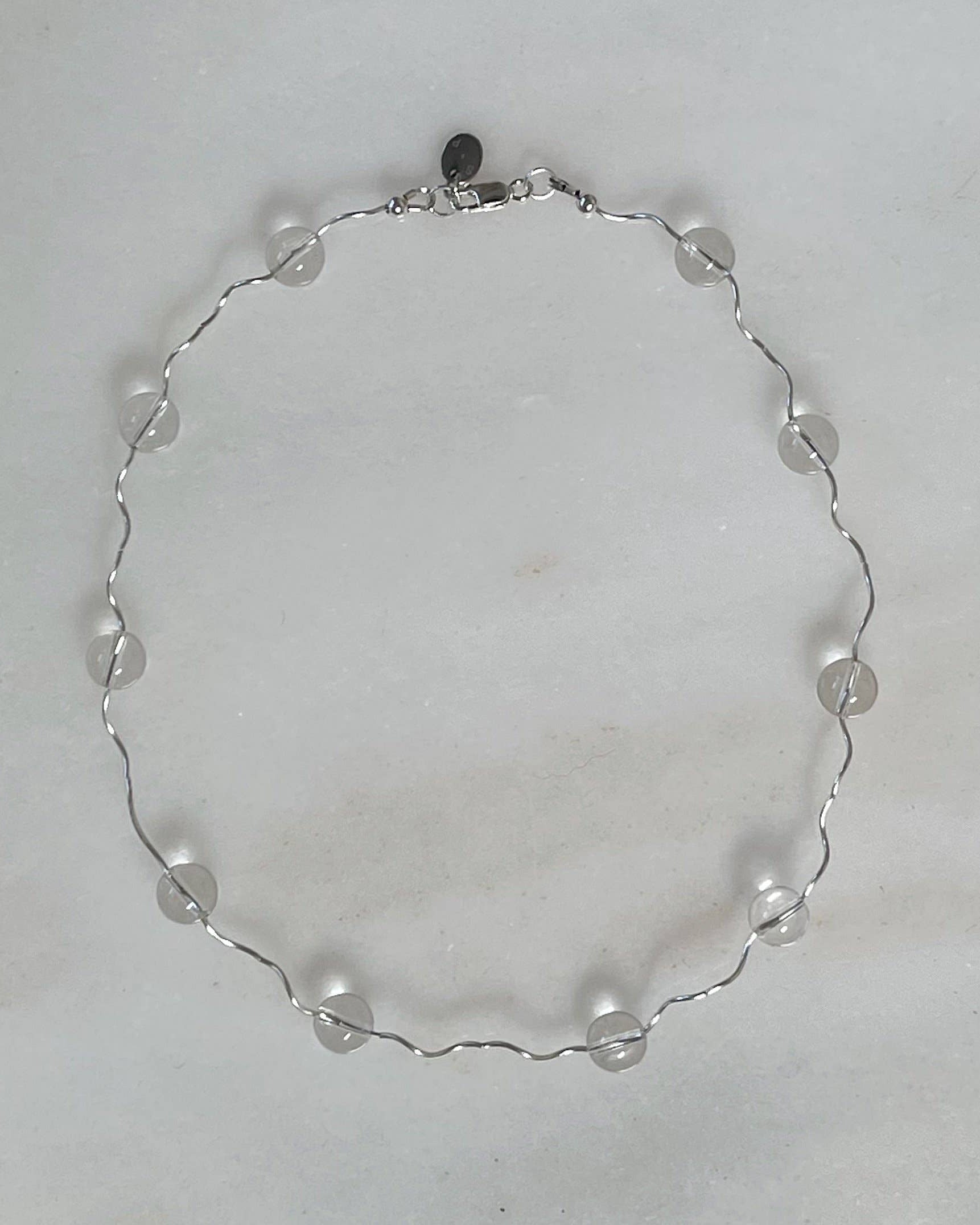 Silver necklace with clear beads on a light gray background