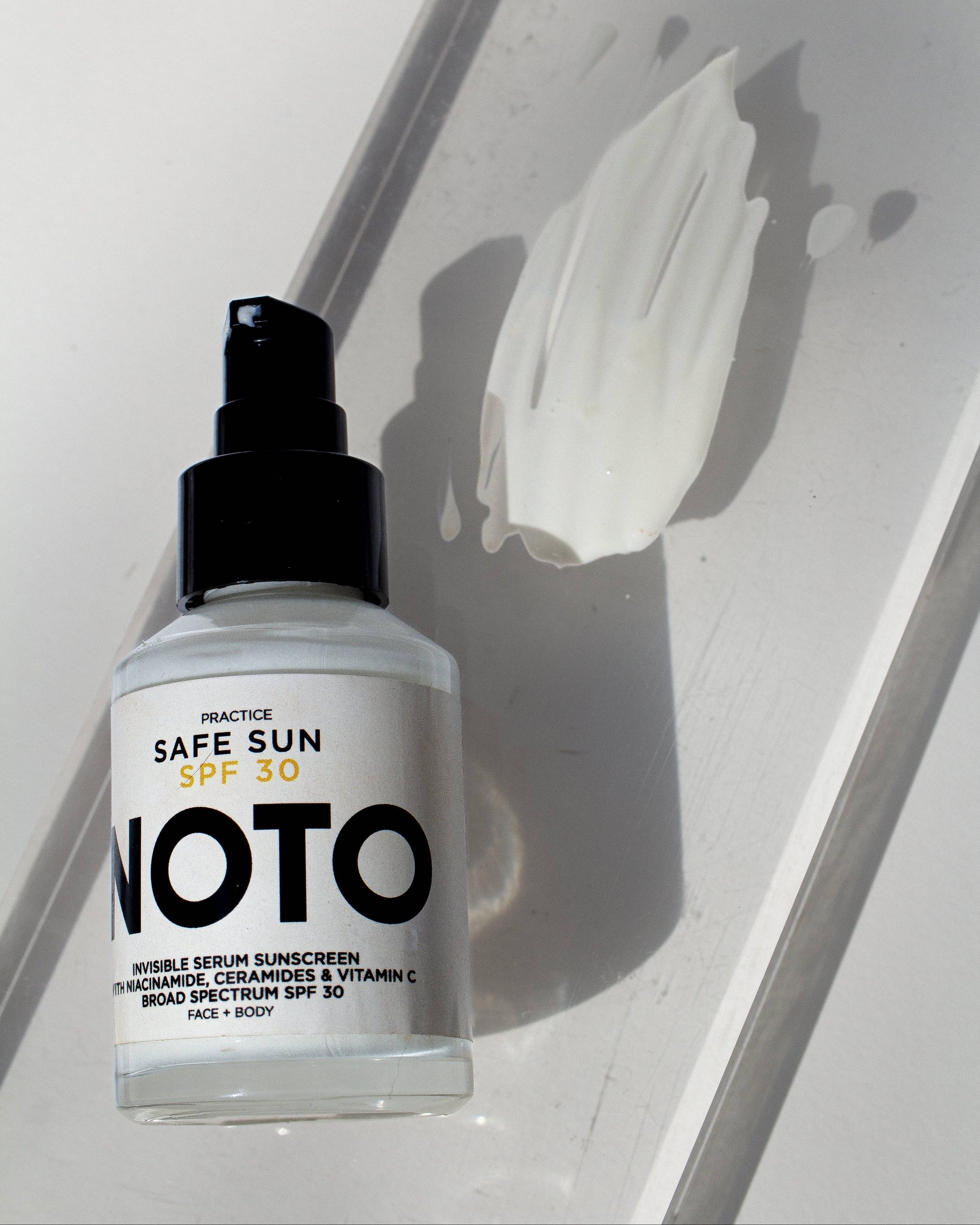 Bottle of NOTO sunscreen serum on a reflective surface