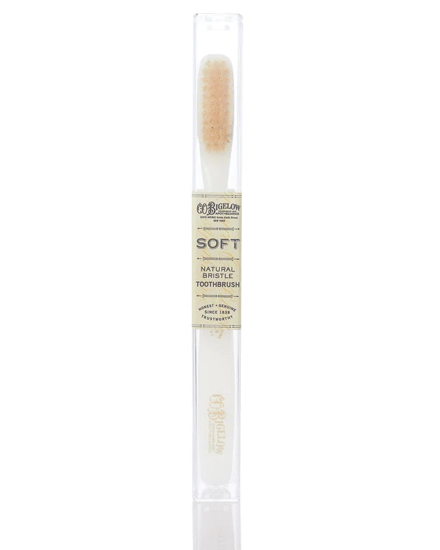 A single toothbrush in a clear cylindrical package with a cream-colored label reading 'M. BELLIN SOFT NATURAL BRISTLE TOOTHBRUSH'.