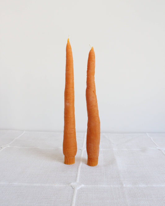 Two orange candles on a white tiled surface