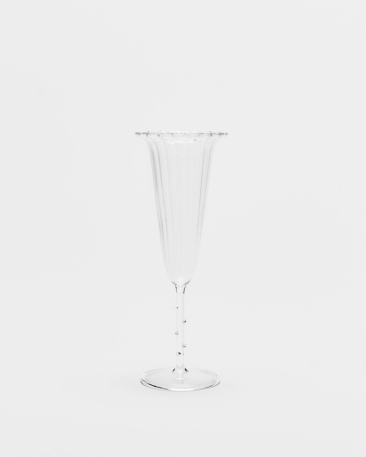 A clear fluted champagne flute with a flared rim and a slender stem, shown against a plain white background.