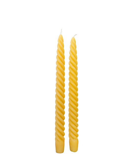 Two twisted yellow candles on a white background
