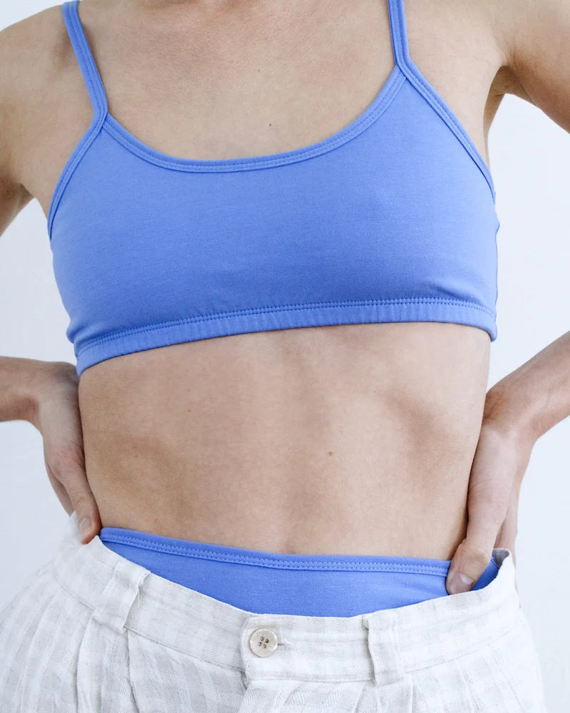 Person wearing a blue sports bra and white pants on a plain background
