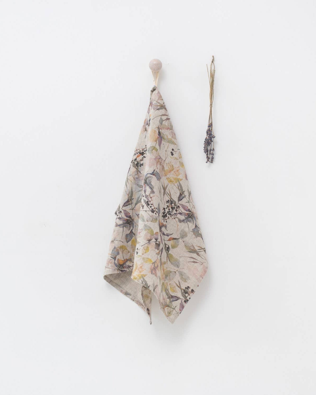 Floral-patterned towel hanging on a hook against a white wall