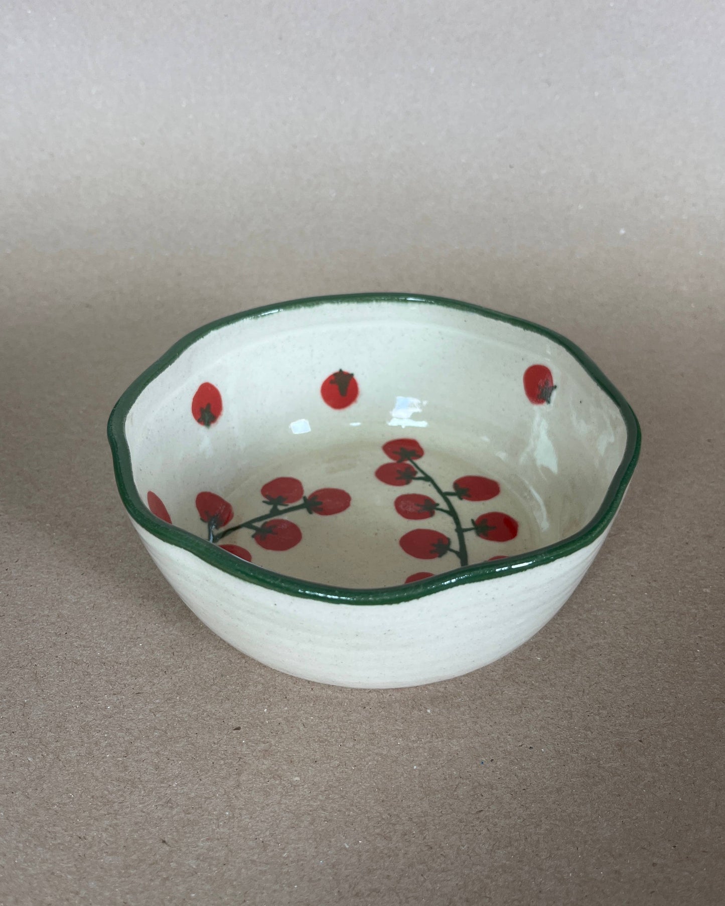 Small ceramic bowl with red berry design on a plain background