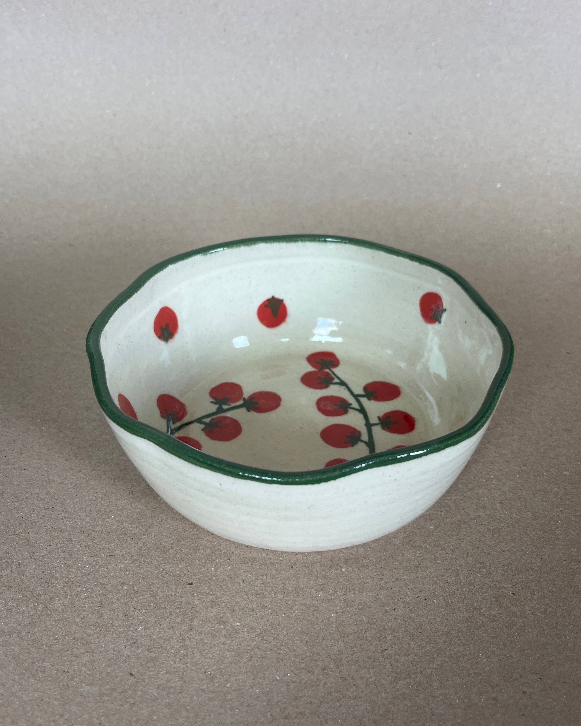 Small ceramic bowl with red berry design on a plain background