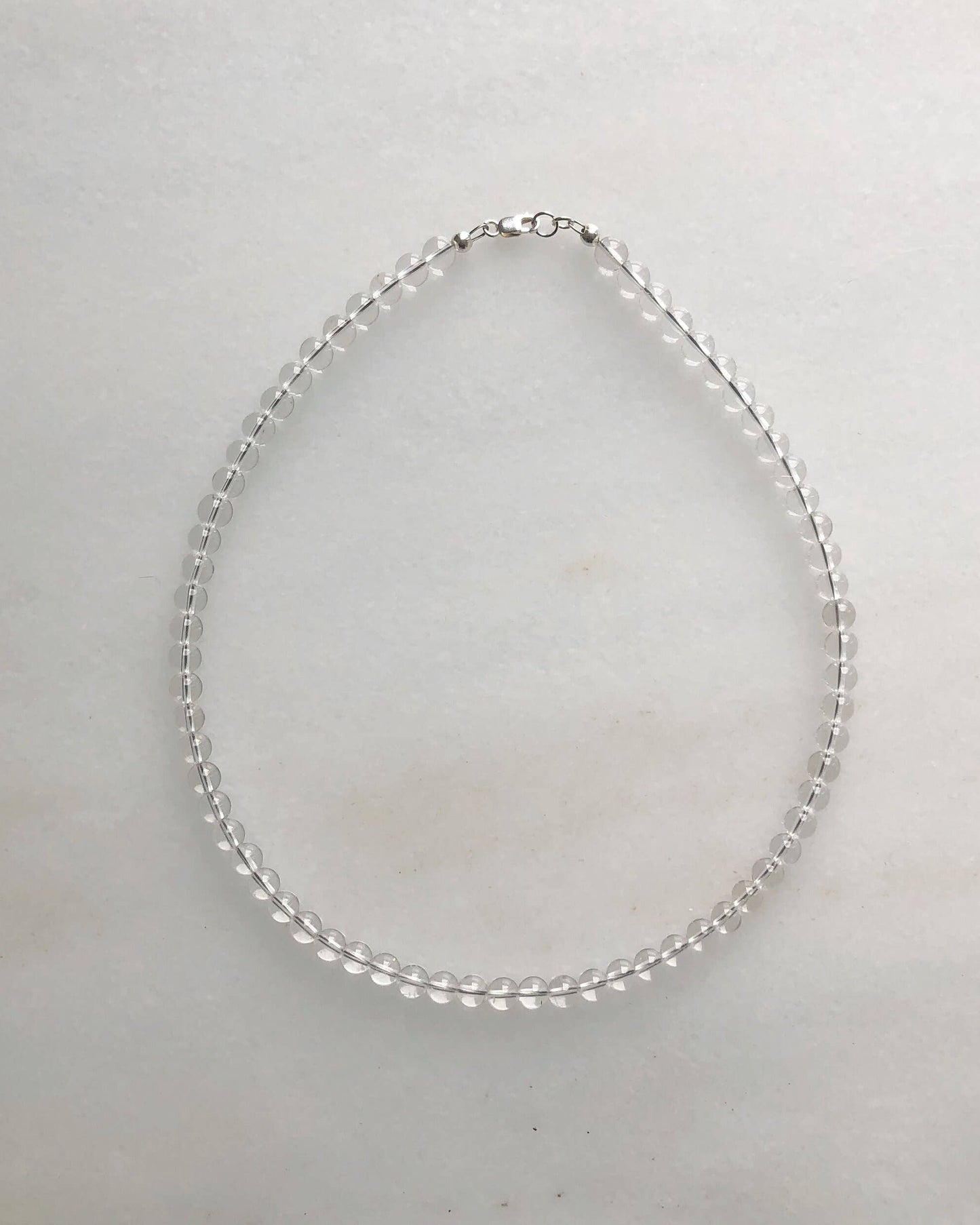 Silver necklace on a light gray background