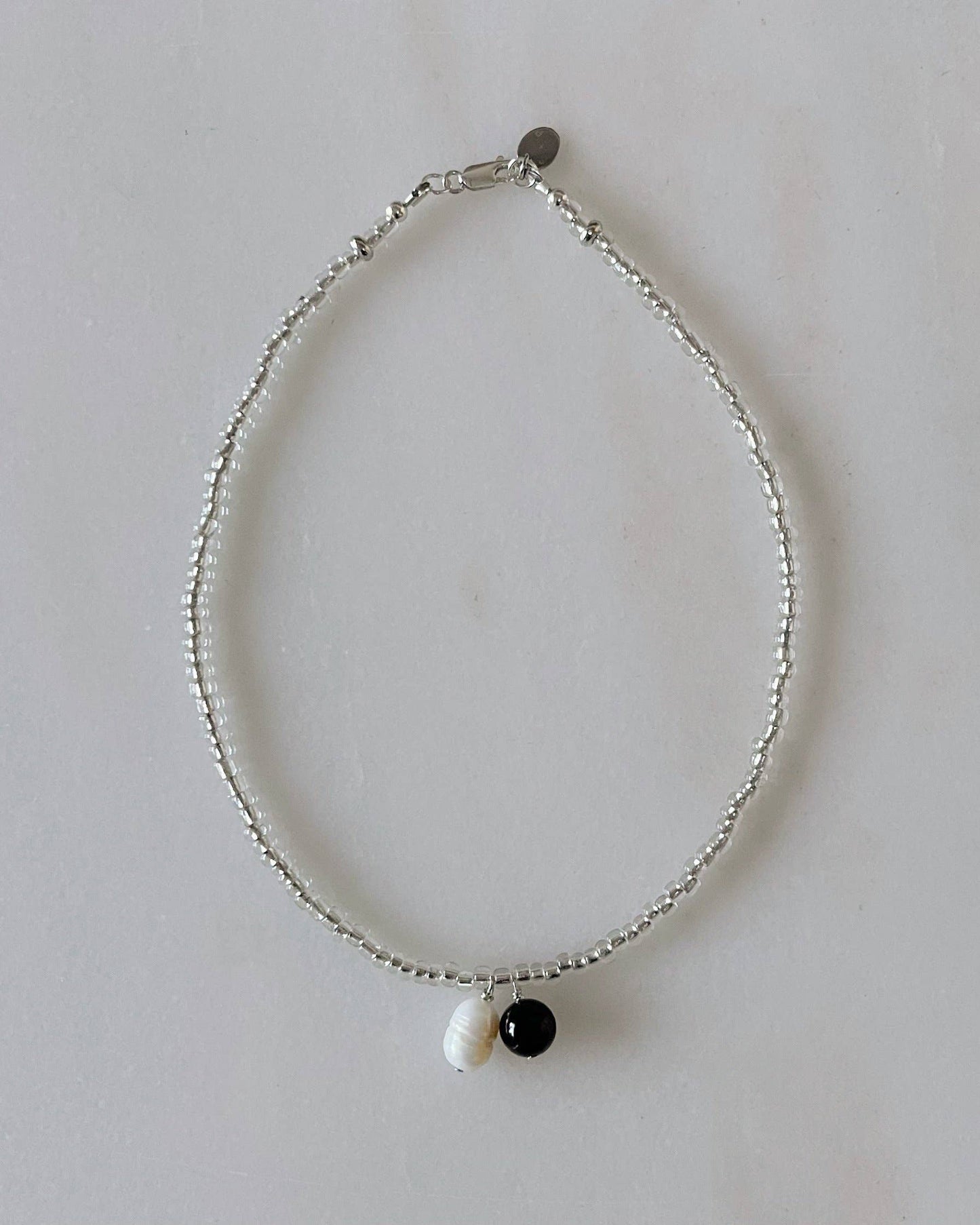 Necklace with three beads on a light gray background