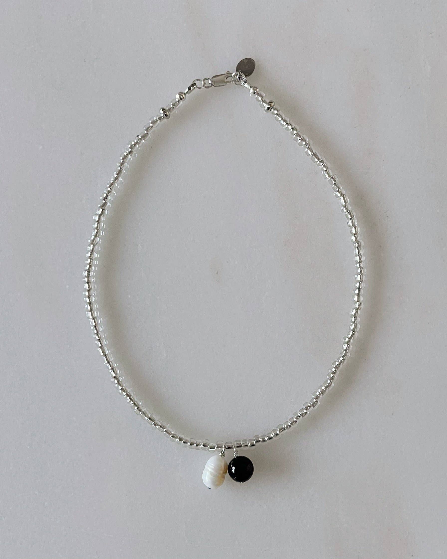 Necklace with three beads on a light gray background