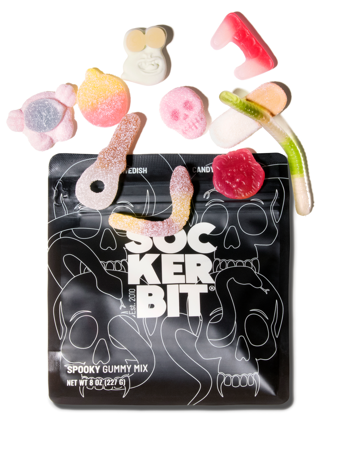A bag of Sock Ker Bit Spooky Gummy Mix with several colorful gummy candies scattered above it on a plain white background.