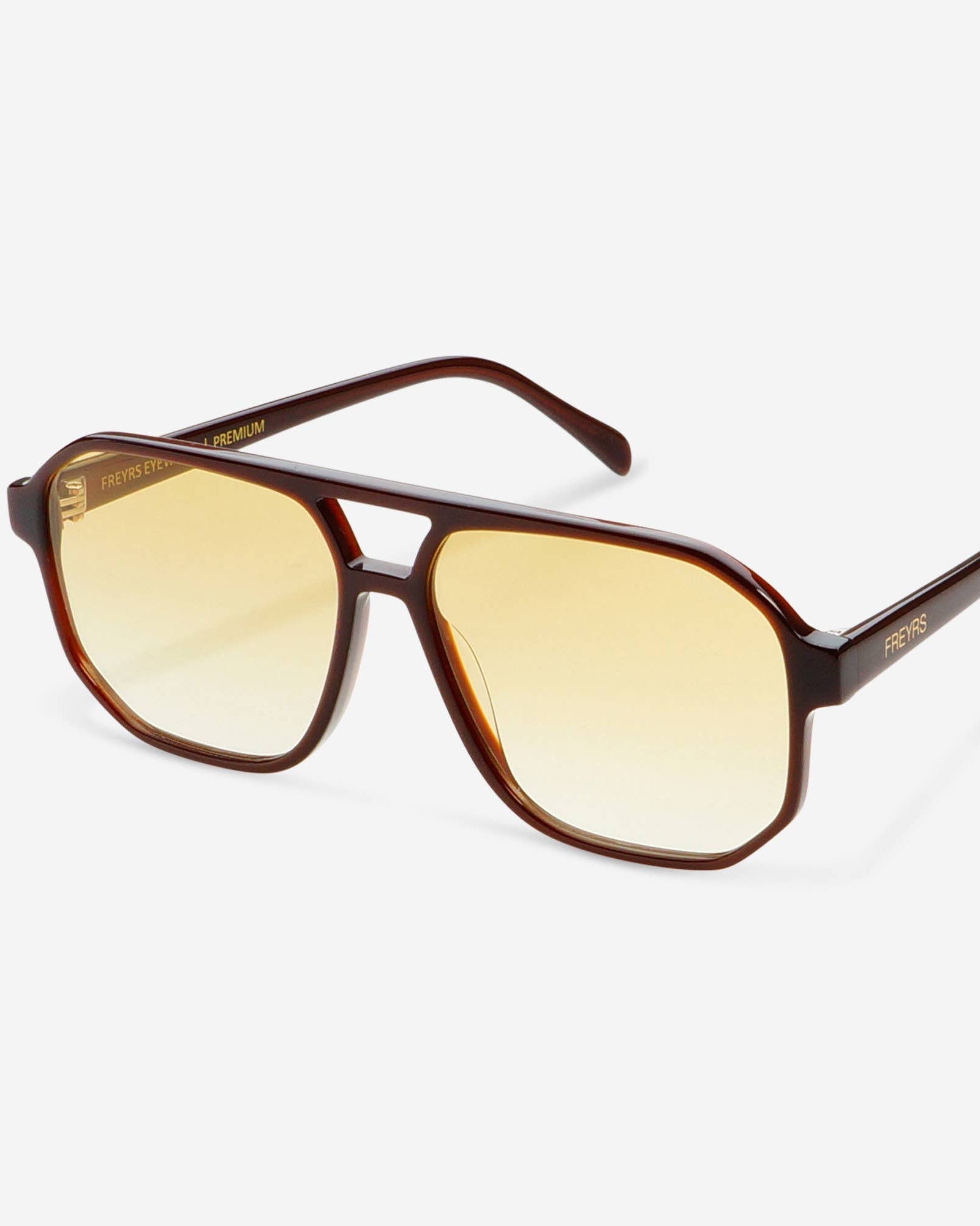 A pair of aviator-style sunglasses with a translucent dark brown acetate frame and gradient yellow lenses, shown on a light gray background.