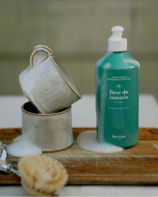 Kerzen bottle of 'fleur de romarin' on a wooden tray with ceramic cups and a scrubber.