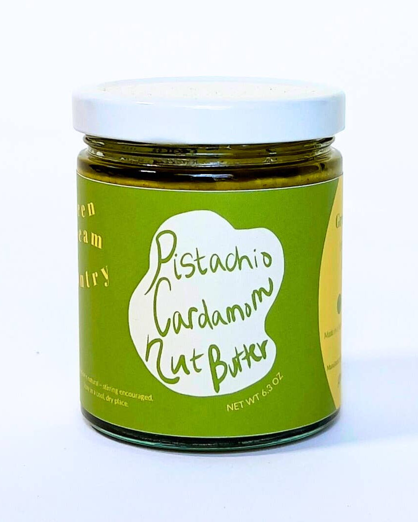 Jar of pistachio cardamom nut butter with a green label on a white background