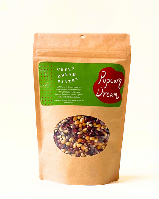 Kraft paper bag with a green label and window displaying mixed seeds, on a white background.