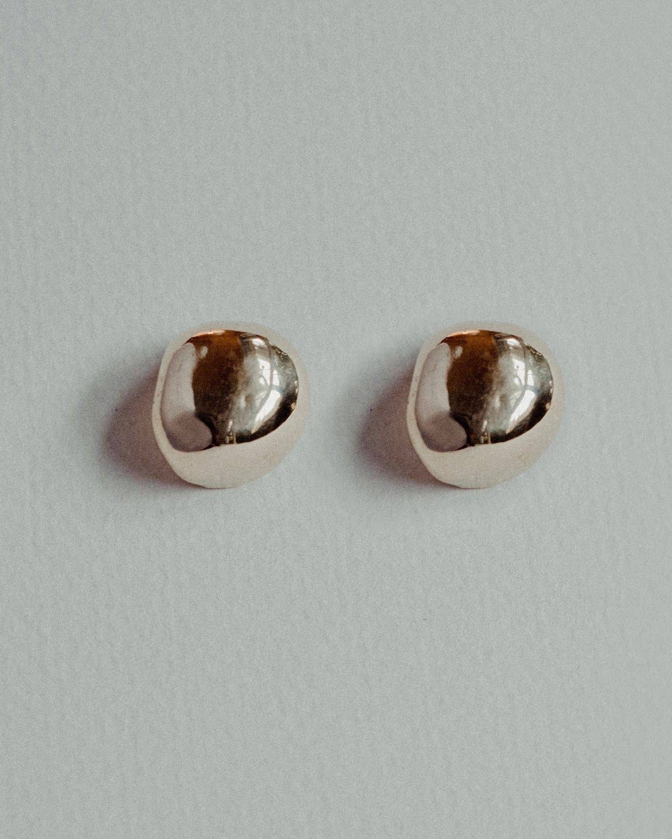 Pair of silver earrings with embedded pearls on a light gray background