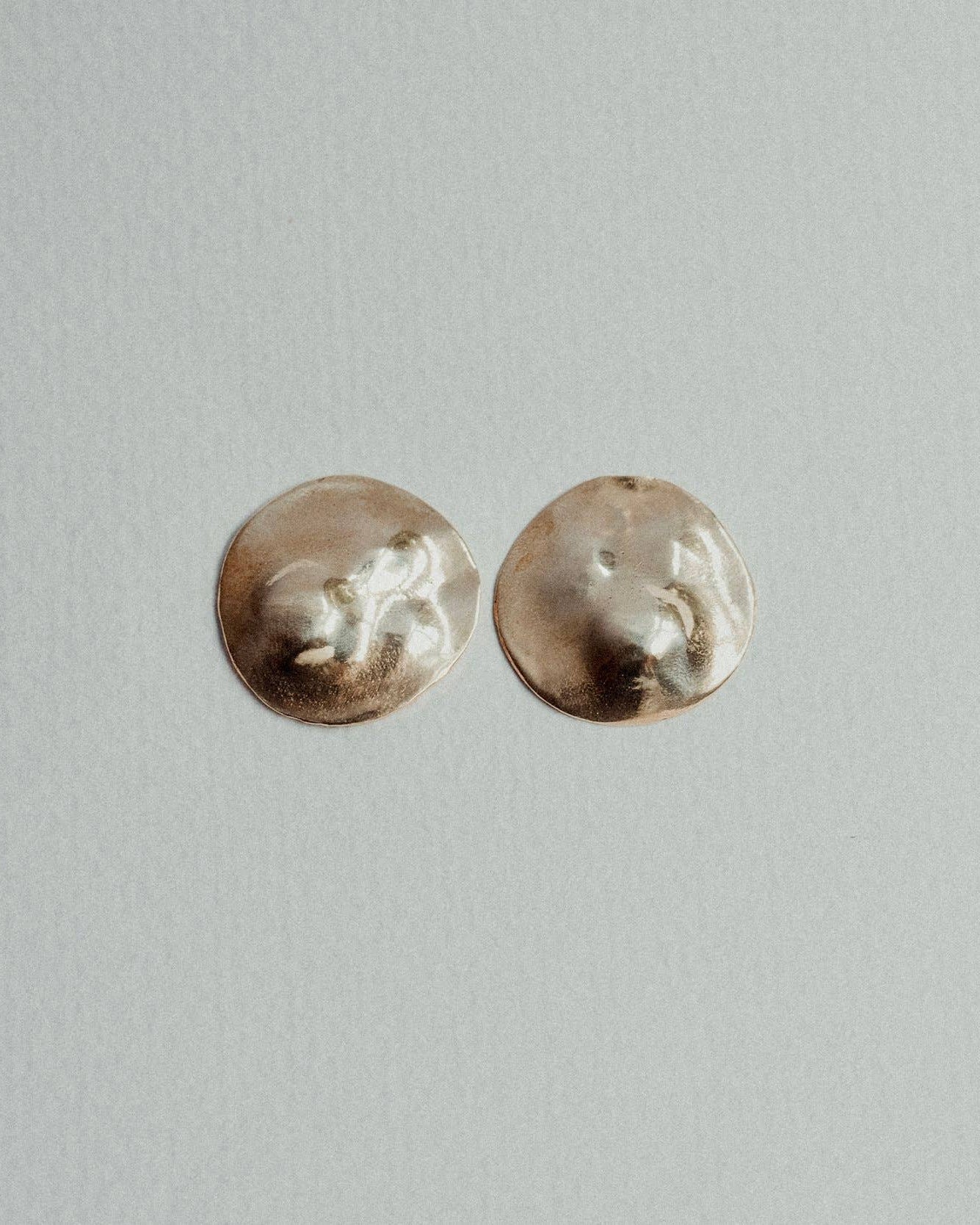 Pair of small round earrings on a light gray background