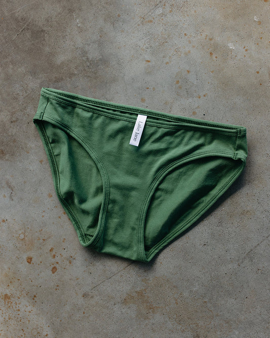 Green underwear with a label on a textured brown surface
