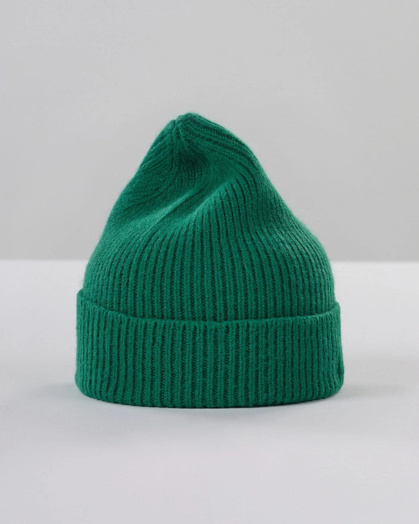 A classic green ribbed knit beanie hat, centered on a clean light gray studio background.