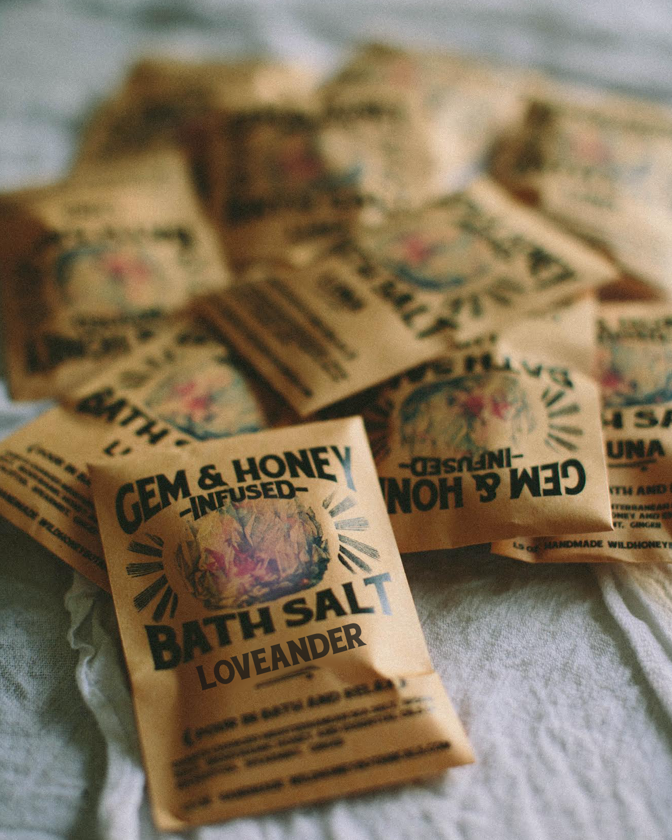 Bath salt packets labeled 'Gem & Honey' on a textured surface