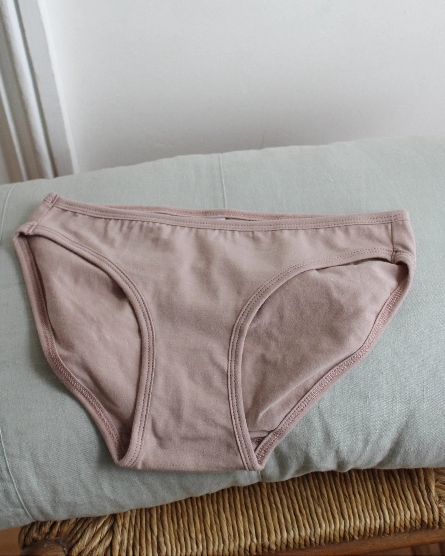 Pink underwear on a light green surface with a neutral background