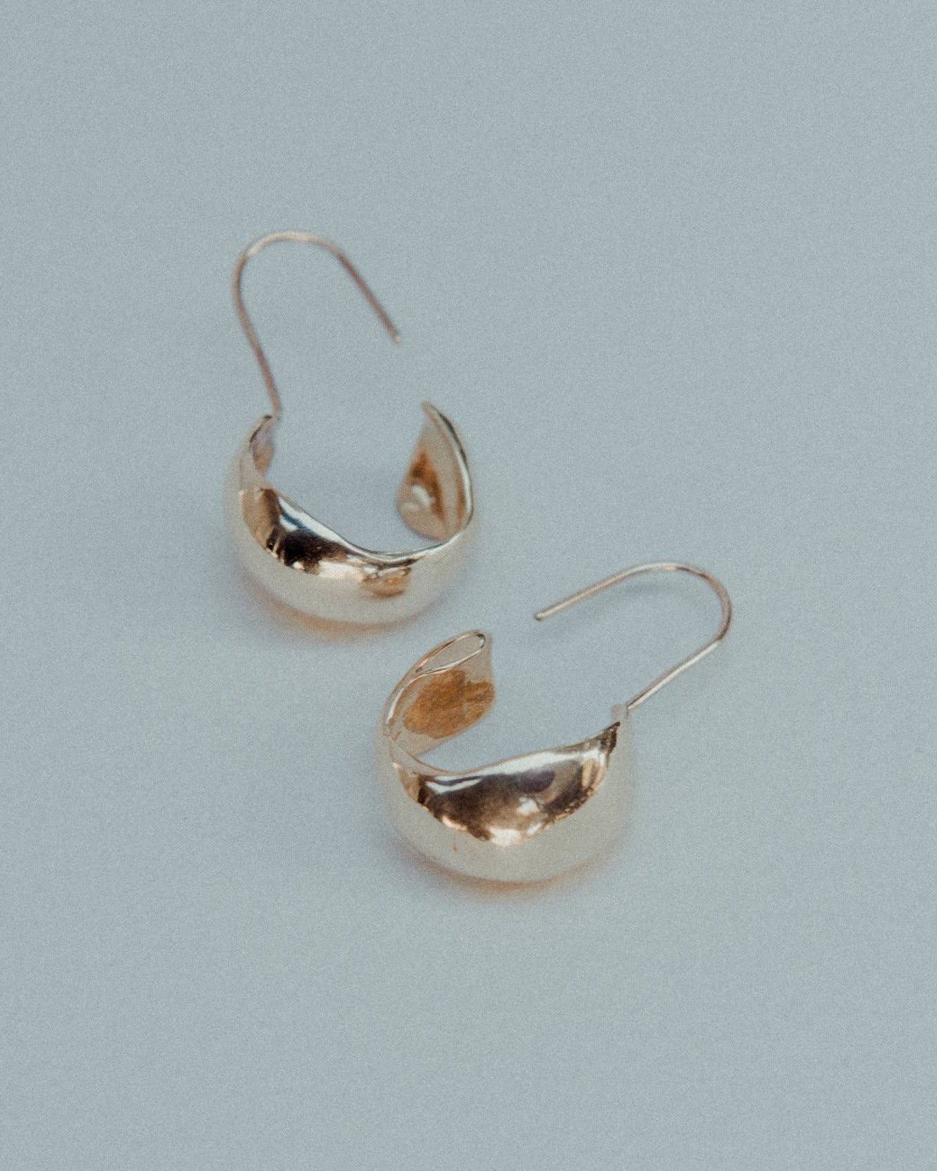 Pair of gold hoop earrings on a light gray background