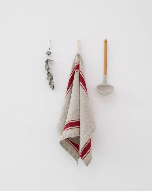 Kitchen towel with red stripes hanging on a hook against a white wall.